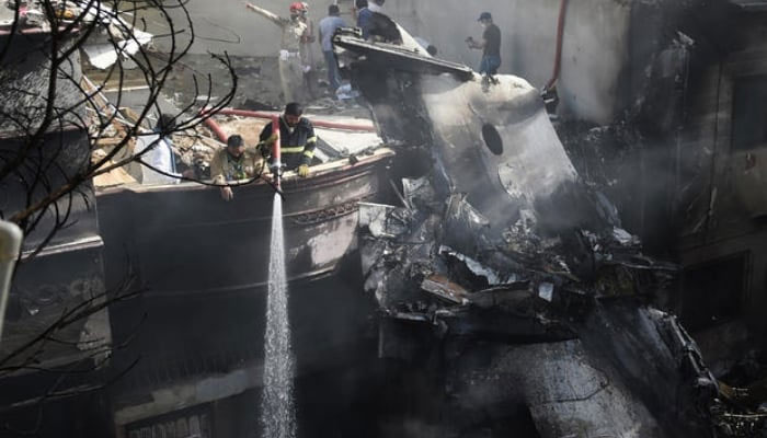 Firefighters spray water on the wreckage of a Pakistan International Airlines aircraft after it crashed at a residential area in Karachi on May 22, 2020. — AFP