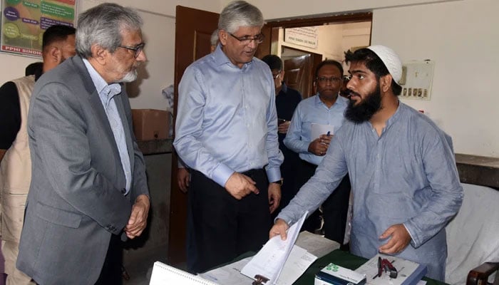 (File photo) Caretaker CM Justice (retd) Maqbool Baqar accompanied by the Health Minister Dr Saad Khalid Niaz (C) checks medicine stock and their entries in the record at Basic Health Unit, Jumma Himayti Goth, Malir on October 10, 2023. — Facebook/Sindh Chief Minister House