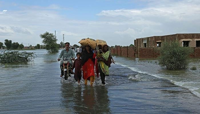 Stranded people wade through a flooded area after heavy monsoon rainfall in Rajanpur district of Punjab province on August 25, 2022. — AFP