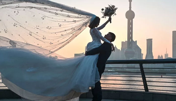 A couple poses for a wedding photo shoot on the Bund promenade along the Huangpu River during sunrise in Shanghai on September 7, 2022. — AFP