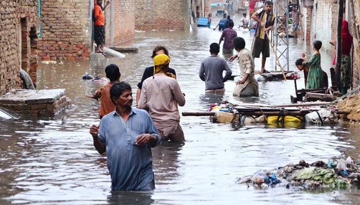 People seen in an inundated street of Jinnah Colony, Latifabad in Hyderabad on August 20, 2022. — APP