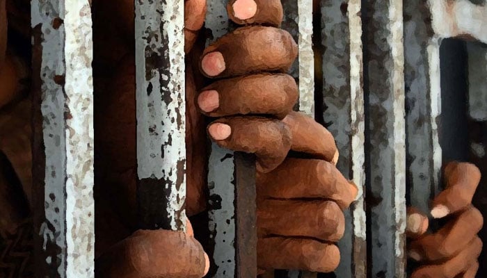 A representational image of men holding on to bars while being in prison. — AFP/File