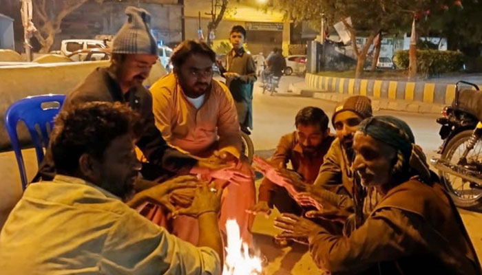 People warm their hands on bonfire to save themselves from cold waves after downpour of heavy winter season in Karachi on March 2, 2024. — PPI