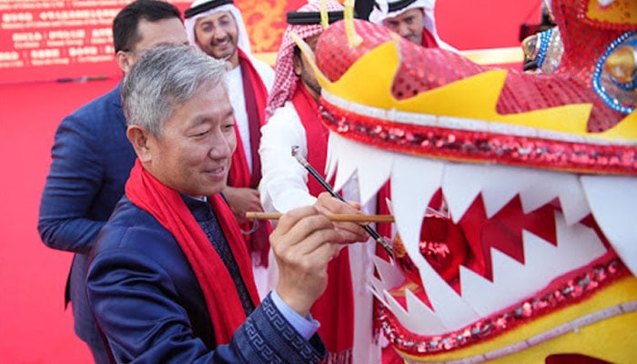 A person paints on a dragon to celebrate the Chinese New Year. — People Arabic