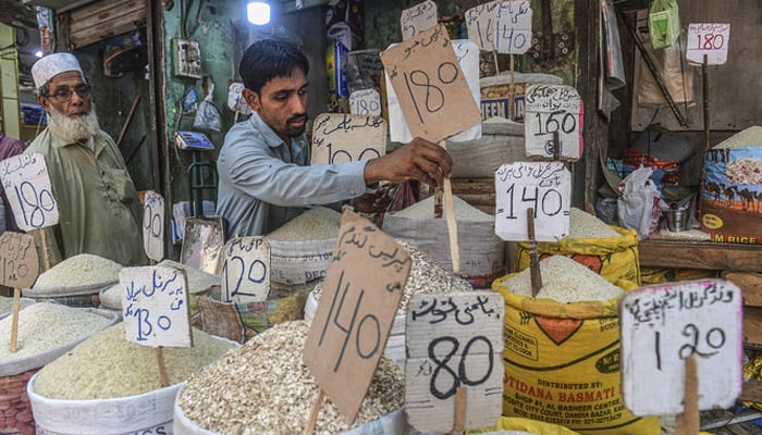 A shopkeeper places a price tag on rice at a shop. — AFP/File