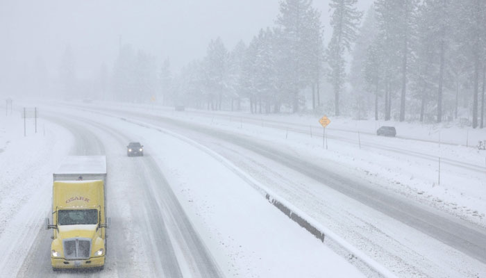 Vehicles drive on I-80 as Snow falls north of Lake Tahoe in the Sierra Nevada mountains during a powerful winter storm in Truckee, California on March 01, 2024. — AFP