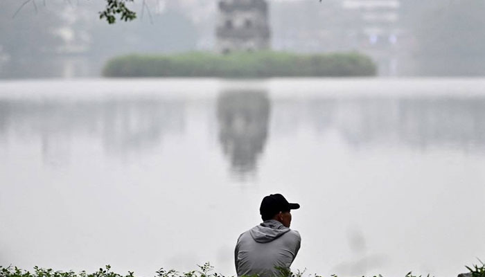 A man sits on the edge of Hoan Kiem Lake in Hanoi on March 4, 2024. — AFP