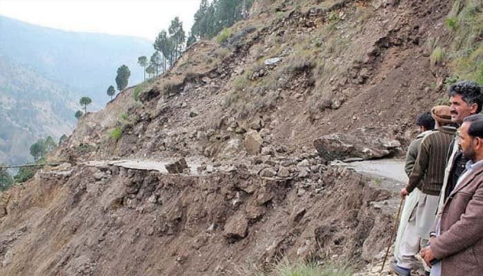 This picture shows people standing near a landslide site. — Geo Tv/File