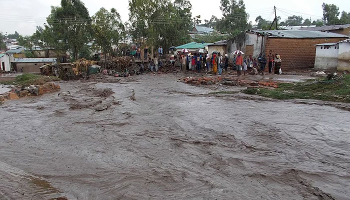 Villagers stand near a flooding street in a township on the outskirts of Blantyre in Malawi. — AFP/File