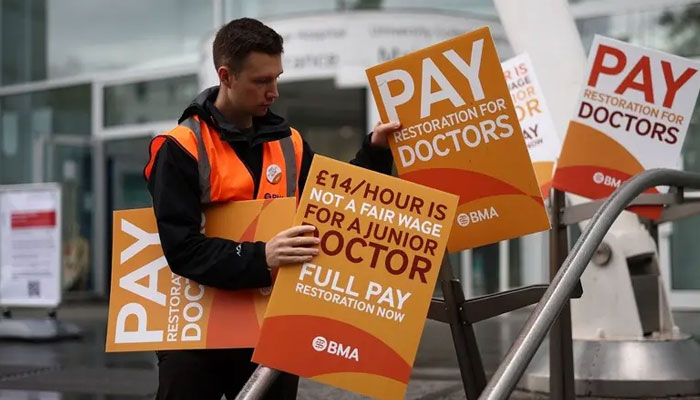 A health worker protests and holds placards calling for better pay outside University College Hospital in central London during a strike by junior doctors on August 14, 2023. — AFP
