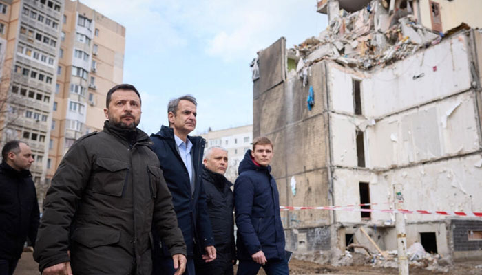 Ukraines President Volodymyr Zelensky (L) and Greeces Prime Minister Kyriakos Mitsotakis, second from left, walking in front of a residential building damaged as a result of a Russian drone attack in Odesa on March 6, 2024. — AFP