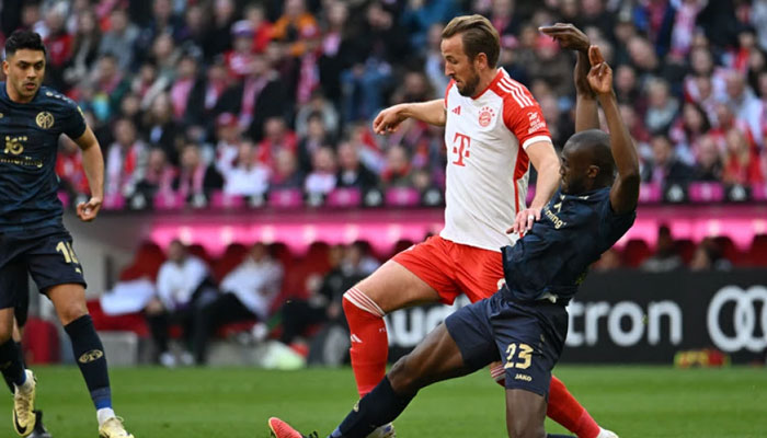 Bayern Munichs Harry Kane (C) and Mainzs French midfielder Josuha Guilavogui vie for the ball during the German first division Bundesliga football match FC Bayern Munich vs 1. FSV Mainz 05 in Munich, Germany on March 9, 2024. — AFP