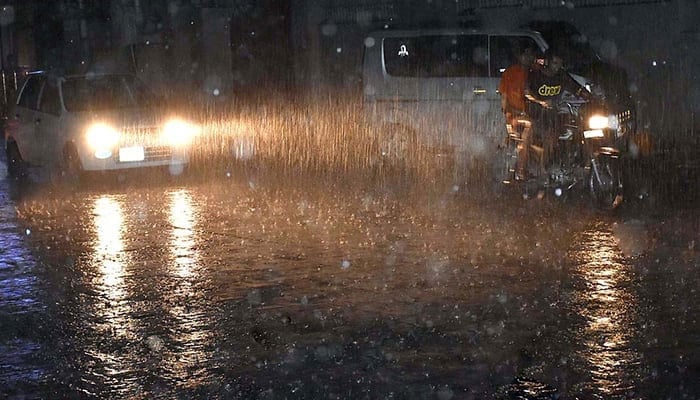 People commuting during heavy rain in Sialkot. — APP/File