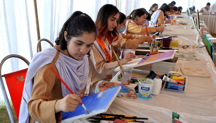 Students painting during Science & Art Exhibition at City University organized by Peshawar Model Degree Colleges. — APP/File