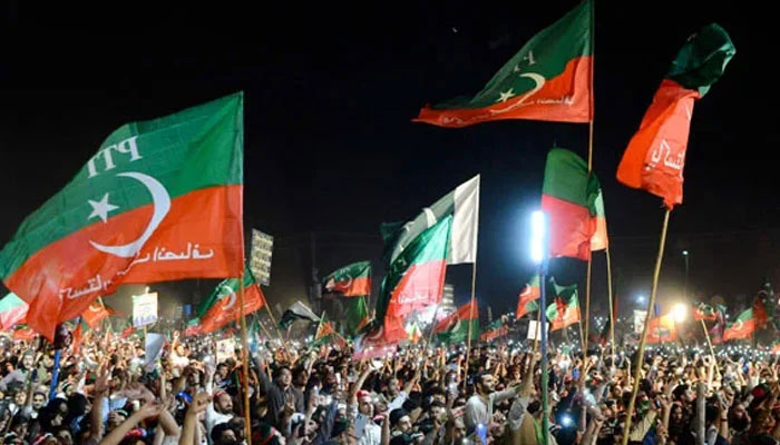 PTI Supporters and workers holds flags at an election rally. — AFP/File