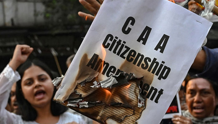 Activists shout slogans as they burn a copy of the Citizenship Amendment Act (CAA) bill during a protest rally in Kolkata on March 12, 2024. — AFP