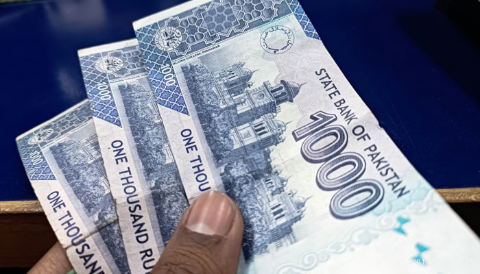 This image taken on January 12, 2024, shows a person holding Pakistani Rupee notes in Karachis II Chundrigar Road. — Geo.tv/Saad Aalam Angaria