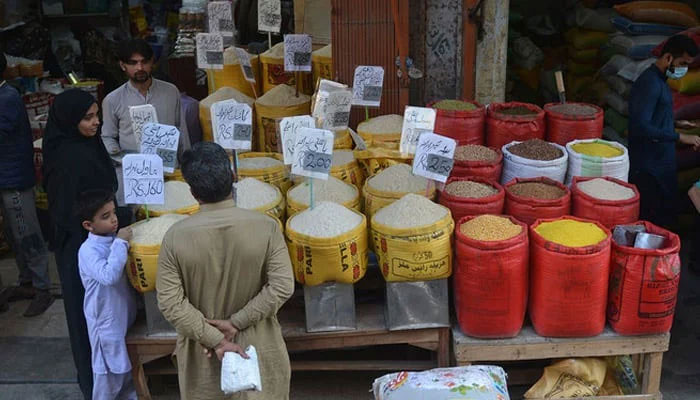 People buy pulses and grains at a wholesale market in Karachi on February 1, 2023. — AFP