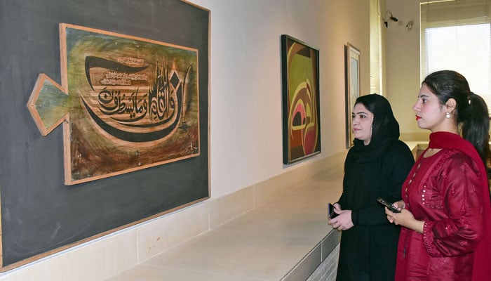 Visitors look at a painting of Quranic Ayat during an Art Exhibition at the Pakistan National Council of the Arts (PNCA) in Islamabad on March 14, 2024. — Online