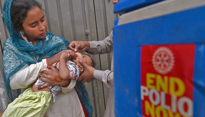 A health worker administers polio vaccine drops to a child during a door-to-door polio vaccination campaign in Lahore, Pakistan, on May 23, 2022. —AFP/File