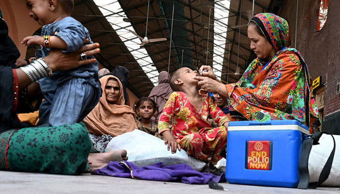 A health worker administers polio drops to a child at a railway station during a polio vaccination campaign in Lahore. — AFP/File
