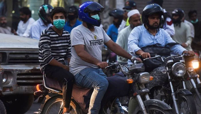 Motorists riding motorbikes along the street in Pakistan. — AFP/Files