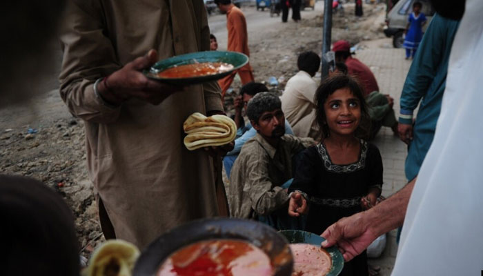 People eat food given out by a charity outside a restaurant. — AFP/File