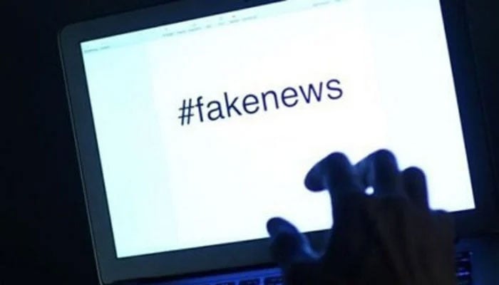 This representational image shows a person using a laptop with fake news written on it. — AFP/File