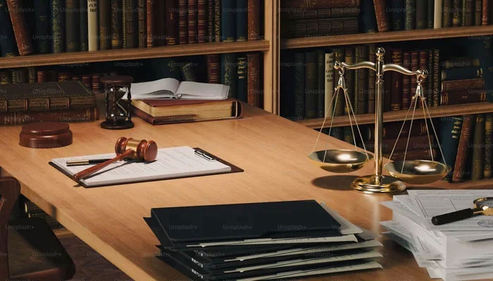 This representational image shows a gavel, scales of justice and law books, documents. — Unsplash/File