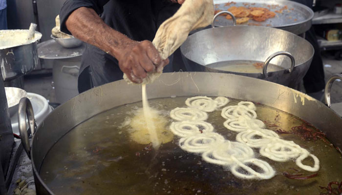 The vendor makes traditional sweet item Jalebi in an oil-filled cauldron on March 19, 2024. — PPI