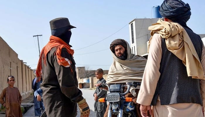 An Afghan security personnel checks a motorbike rider near the site of a suicide bomb attack in Kandahar on March 21, 2024. — AFP