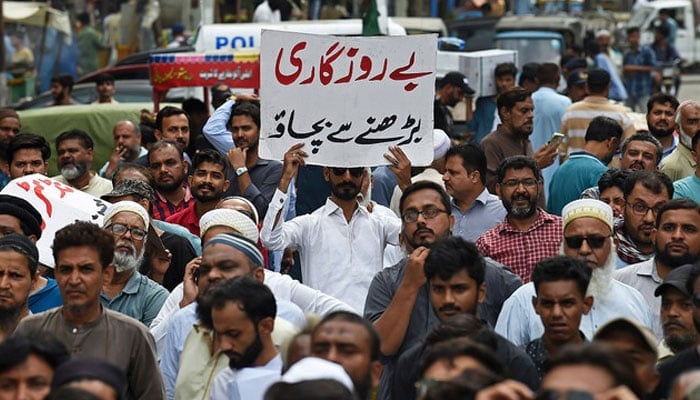 A trader holds a placard reading prevent unemployment from rising during a protest at a street in Karachi on August 23, 2023.—AFP/File