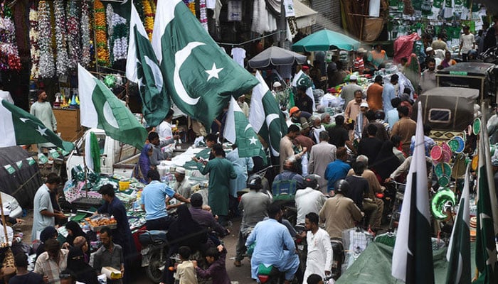 People throng a market where vendors sell Pakistans national flags in Karachi on August 11, 2023. —  AFP