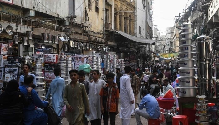 People walk past retail shops at a market in Karachi in this undated photo. — AFP/File