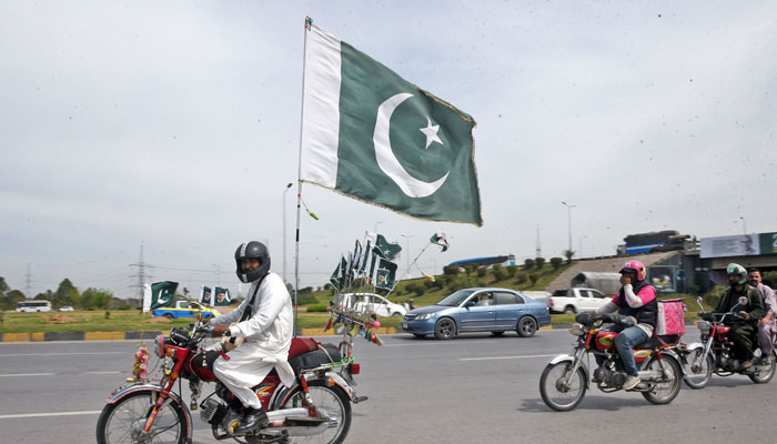 A man decorating his motorcycle with national flags to celebrate the Pakistan Day Parade on March 23, 2024. — Online