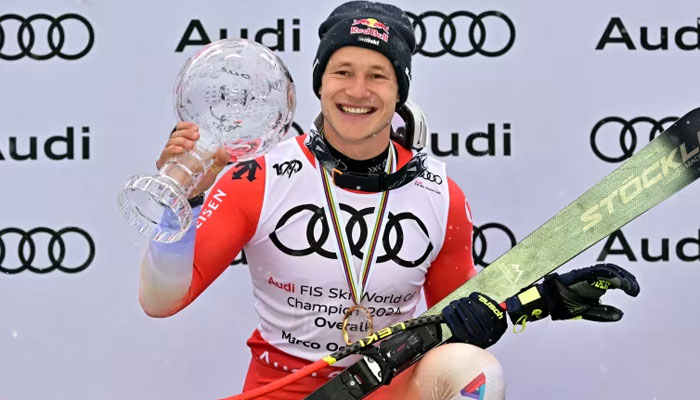Switzerlands Marco Odermatt poses with his Crystal Globe trophy on the podium in Saalbach on March 24, 2024. — AFP