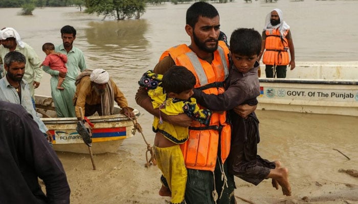 Rescue workers help evacuating flood affected people from their flood hit homes following heavy monsoon rains in Punjabs Rajanpur district on August 27, 2022. — AFP