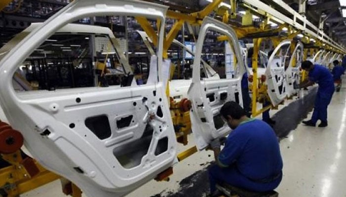 Workers assemble car doors at an automobile manufacture plant. — AFP/File