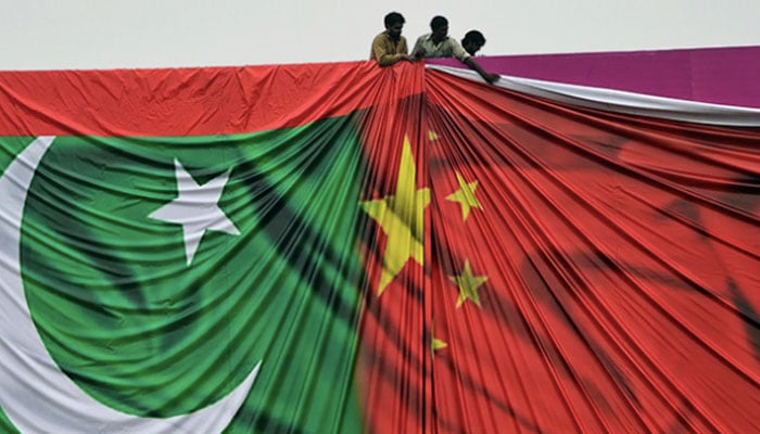 Workers fix a banner depicting flags of Pakistan and China. — AFP/File