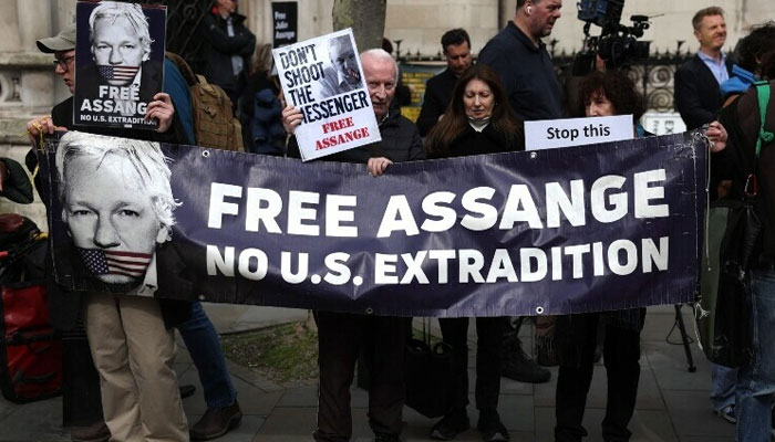 Supporters of WikiLeaks founder Julian Assange hold a banner and placards outside The Royal Courts of Justice, Britain’s High Court, in central London, UK on March 26, 2024 — AFP
