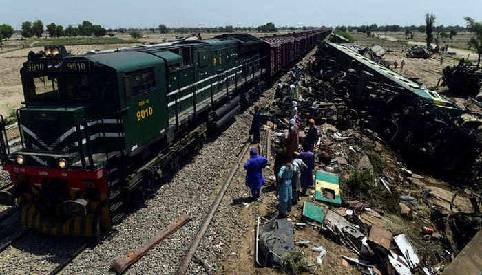 A passenger train passes by the wreckage of a train in Daharki, Pakistan.— AFP/File