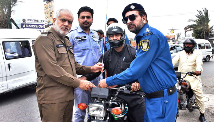 Traffic Police staffer installs free safety wires on motorcycles image released on March 27, 2024. — APP
