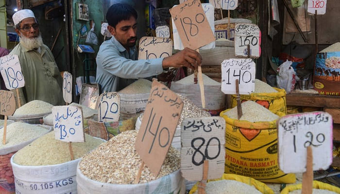 A shopkeeper places a price tag on rice at a shop. — AFP/File