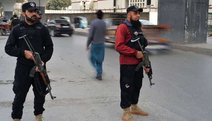 Peshawar Police personnel can be seen standing on a road in the city. — AFP/File