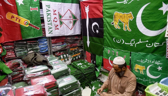 A shopkeeper arranges flags of political parties at his shop before the February 8 general elections in Karachi on January 3, 2024. — APF