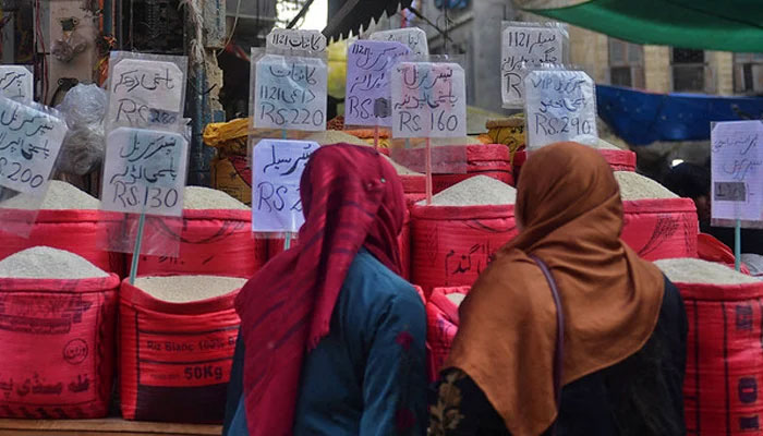 In this picture taken on January 10, 2023, women check rice prices at a main wholesale market in Karachi. — AFP