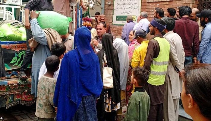 People standing in queue for getting free flour bags under Nigehban Ramazan programme in Lahore on March 11, 2024. — APP