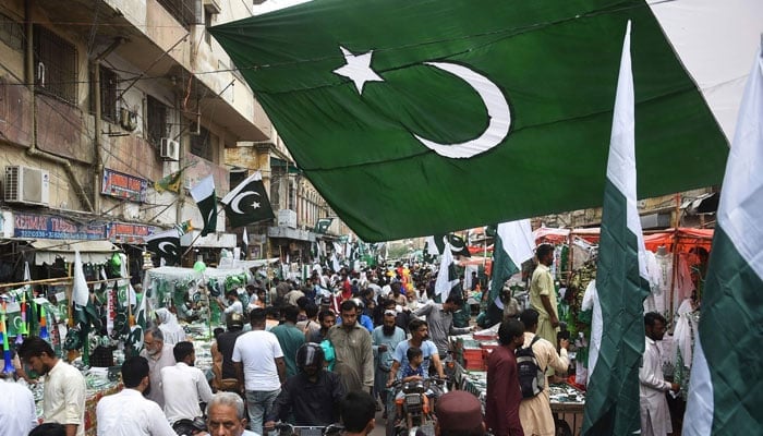 People thorong a market where vendors sell Pakistans national flags in Karachi on August 11, 2023, ahead of the country´s 76th Independence Day. — AFP