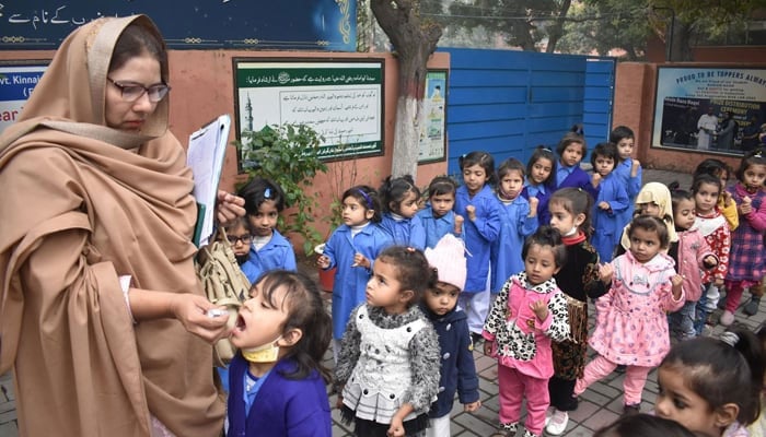 A lady health worker administers polio drops to students at school during a polio eradicating campaign, in Lahore. — Online/File
