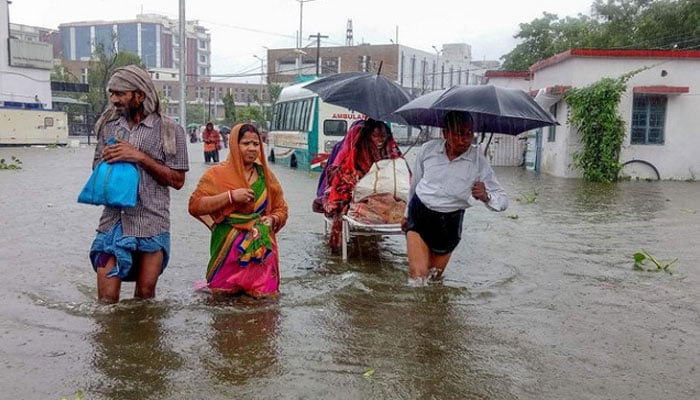 Patients wade through floodwaters on their way to hospital during heavy rain in India. — AFP/File